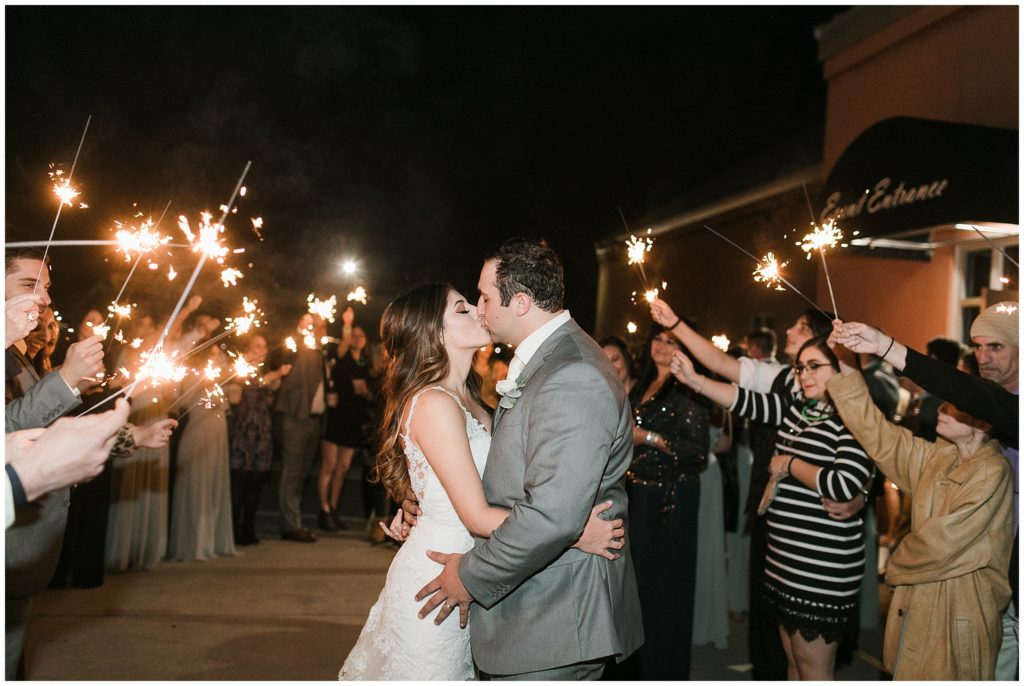 couple kisses during wedding reception exit with sparklers