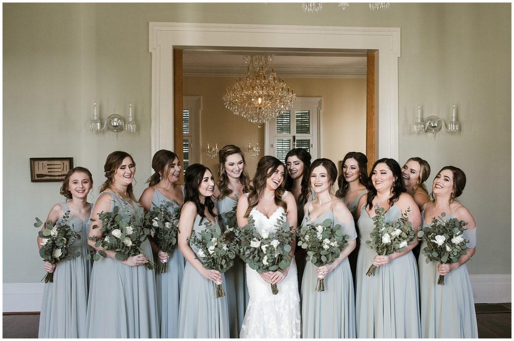bride poses with bridesmaids holding eucalyptus bouquets 