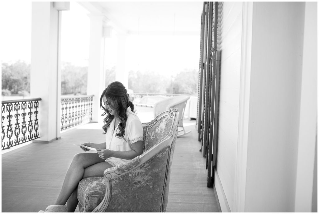 bride sits on a porch and reads a letter from her groom before wedding ceremony