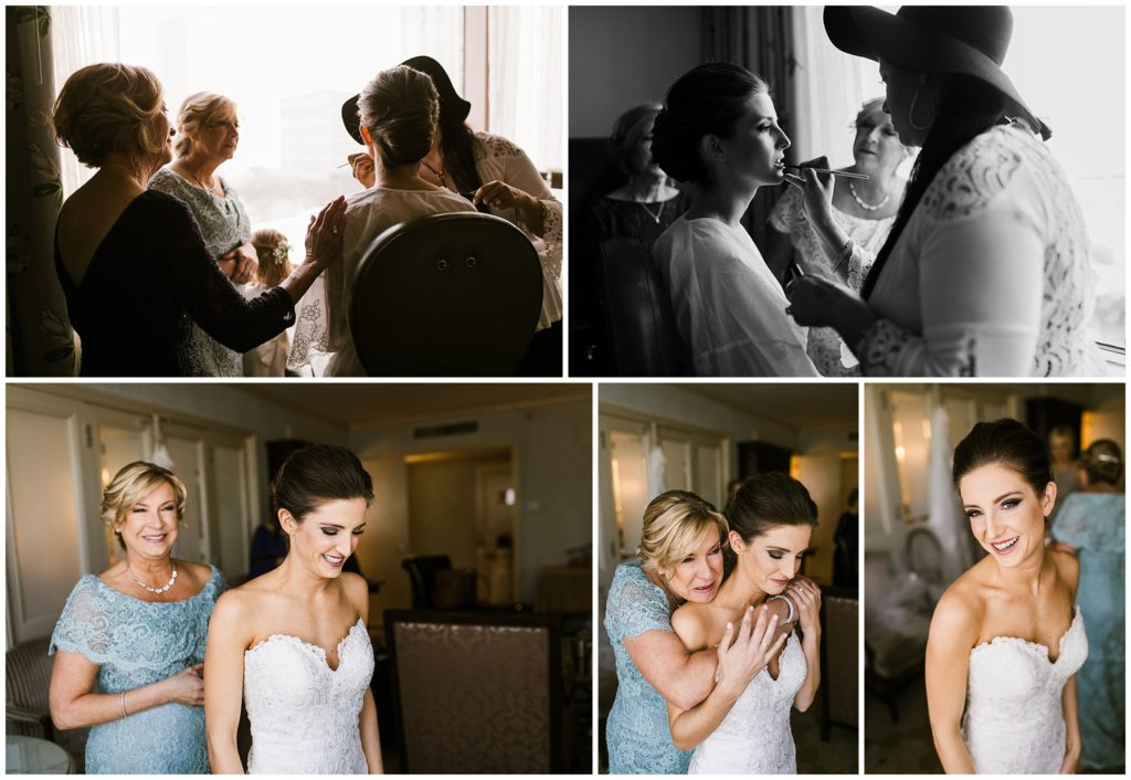 bride gets her makeup done on wedding day and mother of the bride helps bride get into wedding gown