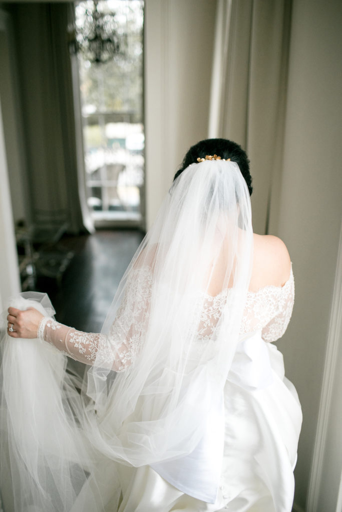 bride holds veil and descends staircase during bridal session