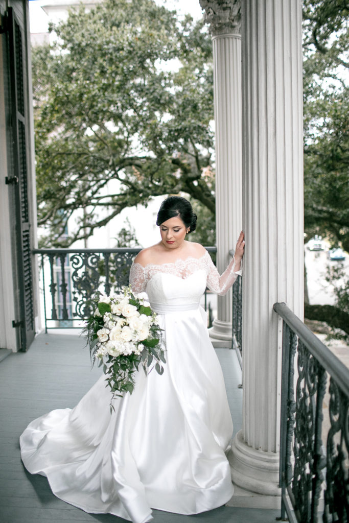 bride poses with large bouquet on porch
