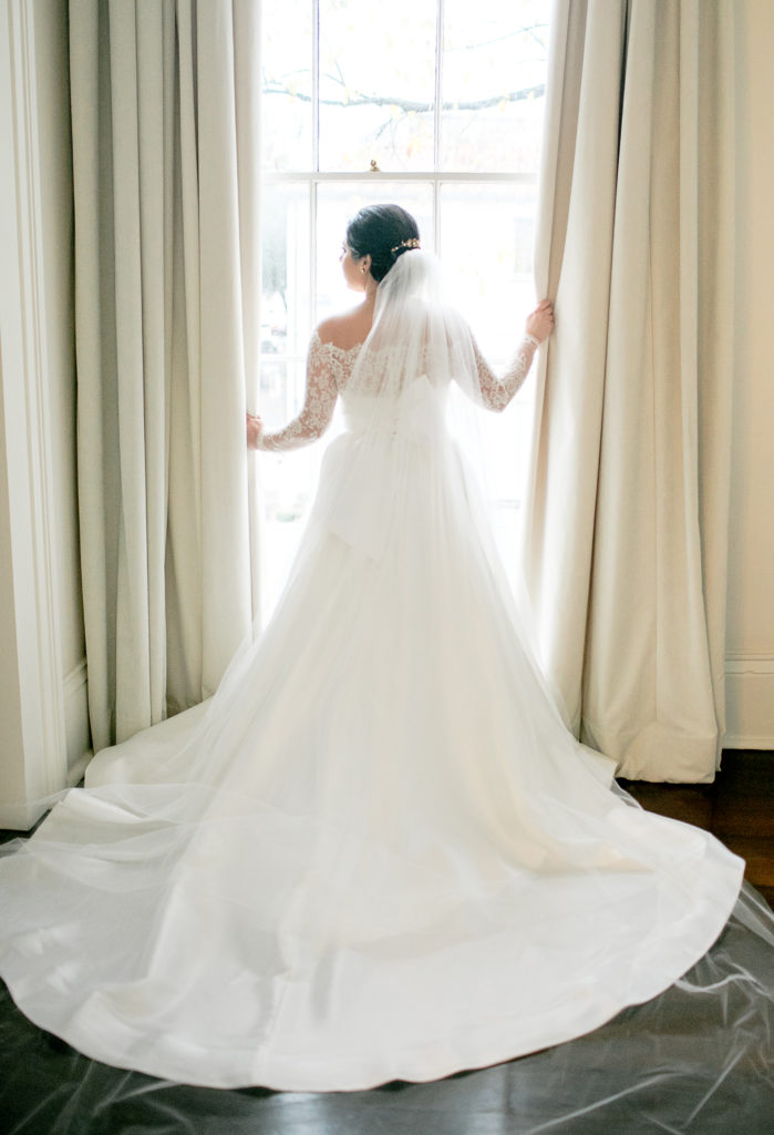 bride poses in front of large window during bridal session