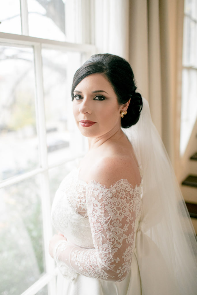 bride stands in front of window during bridal session