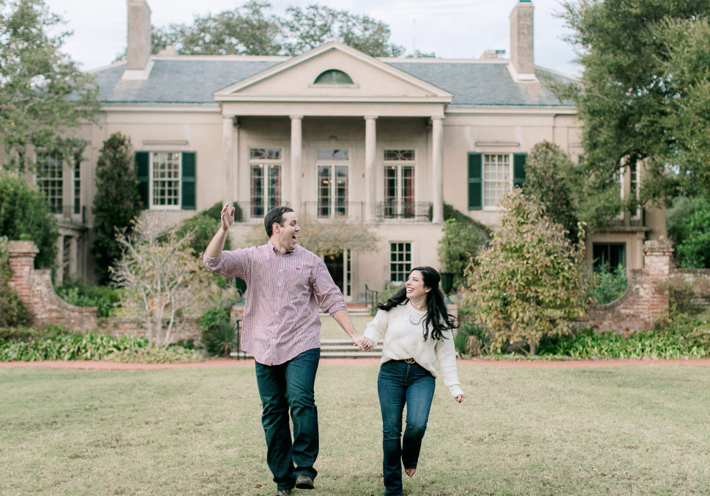Engaged couple running in front of Longue Vue house in New Orleans