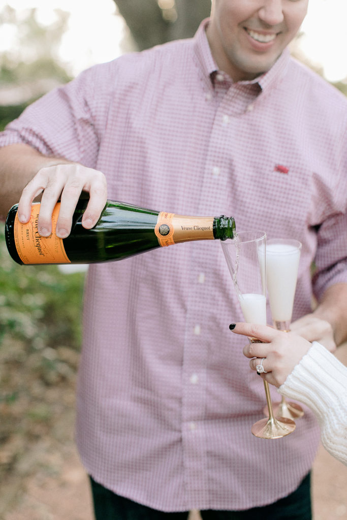 man pours Veuve Cliquot champagne into fiancee glass